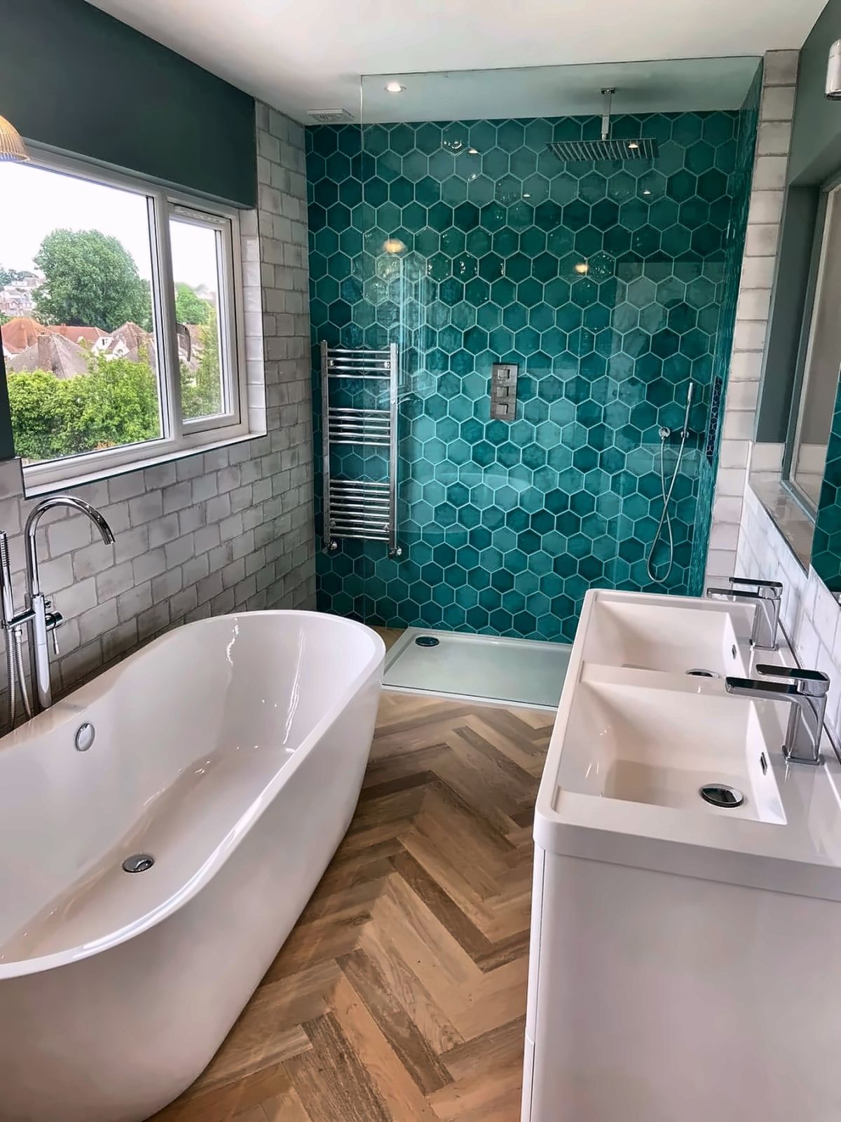 Bathroom with teal hexagon shower tiles, freestanding bath and herringbone floor, fitted by BPB