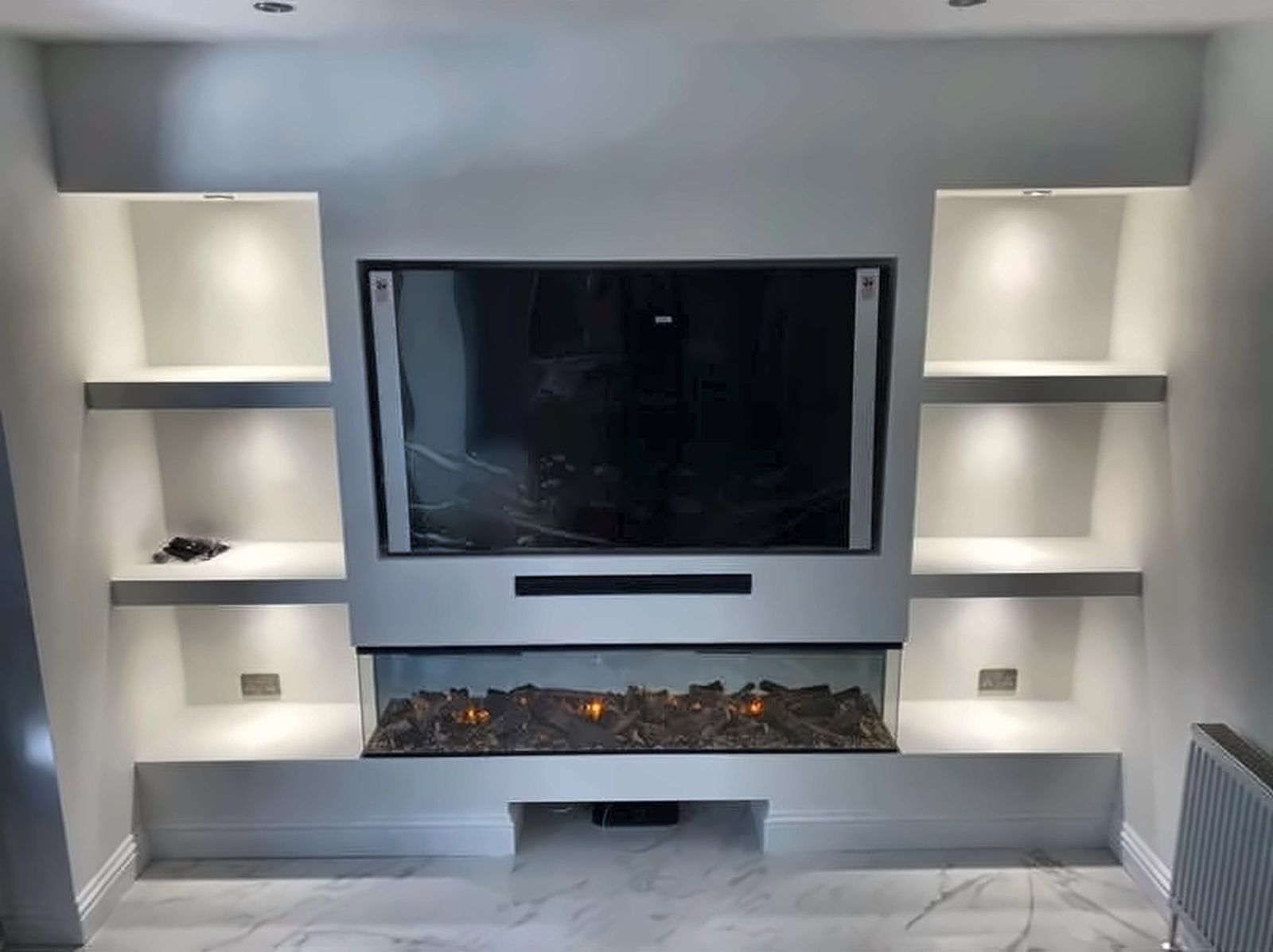 Media wall with lit shelving and fire, built by BPB